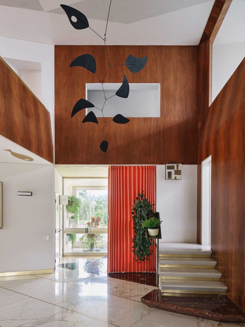 Im Herzen der Villa Planchart entfaltet sich ein Spiel der Kontraste: Kühler Carrara-Marmor trifft auf warmes Tropenholz, geometrische Strenge auf organische Formen. Diese erlesenen Materialien bilden die perfekte Bühne für die exquisite Kunstsammlung der Plancharts. Im Zentrum schwebt ein Mobile von Alexander Calder, dessen filigrane Formen in ständiger Bewegung sind. 
