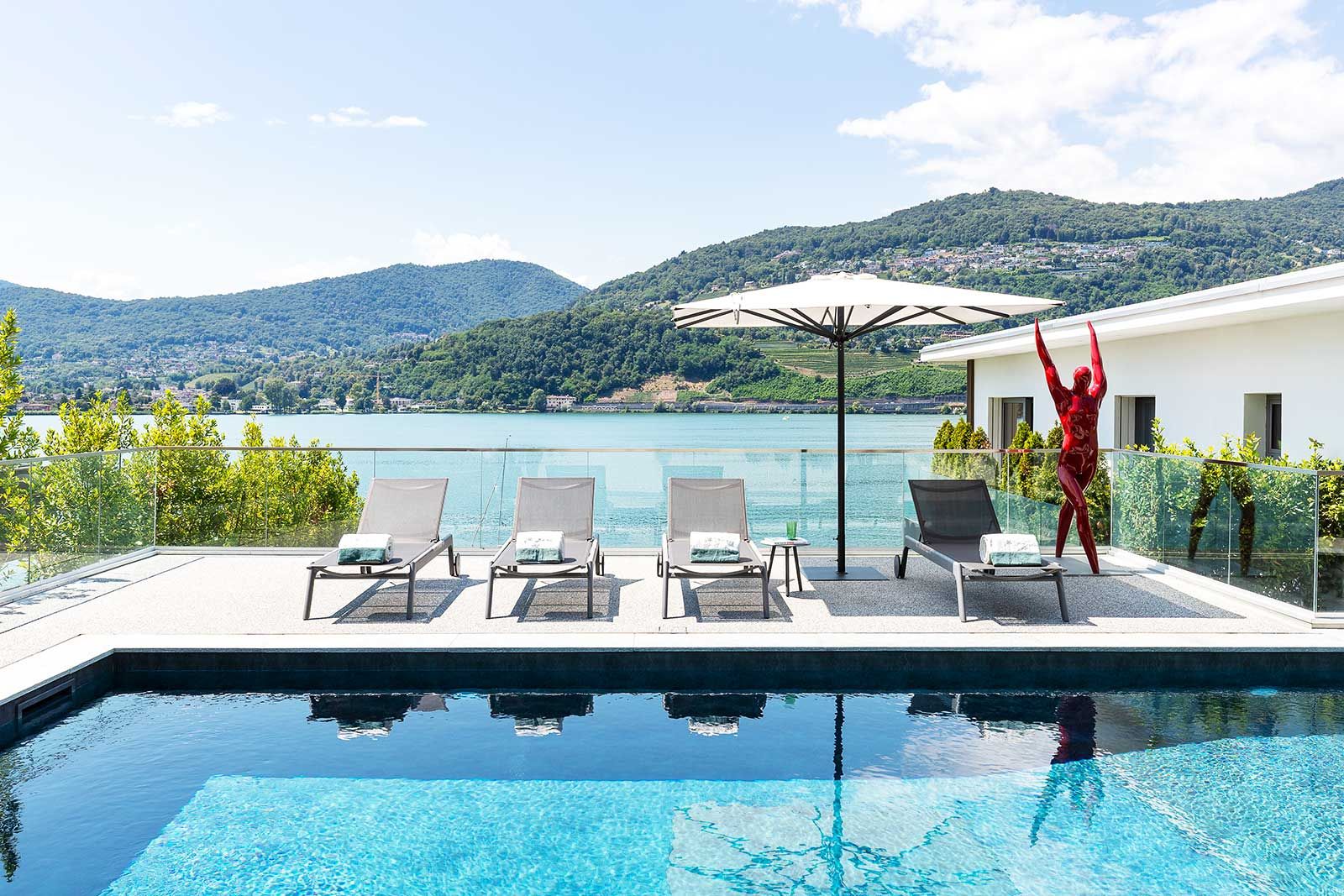 Von der Terrasse fällt der Blick frei auf den See. Die roten Skulpturen sind von Gigi Rigamonti.